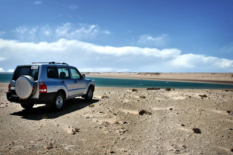 Une voiture de location à sal garée sur le sable au bord de l'eau.