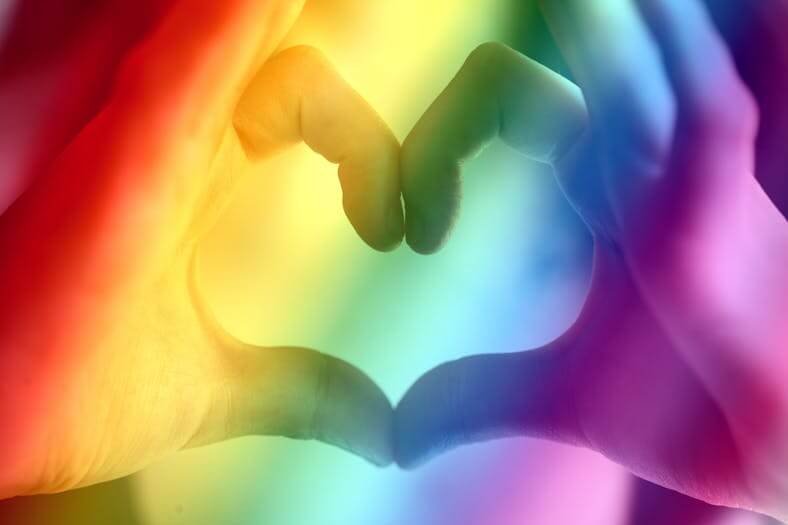 un cour formé avec les deux mains et couleurs lgbt en fond