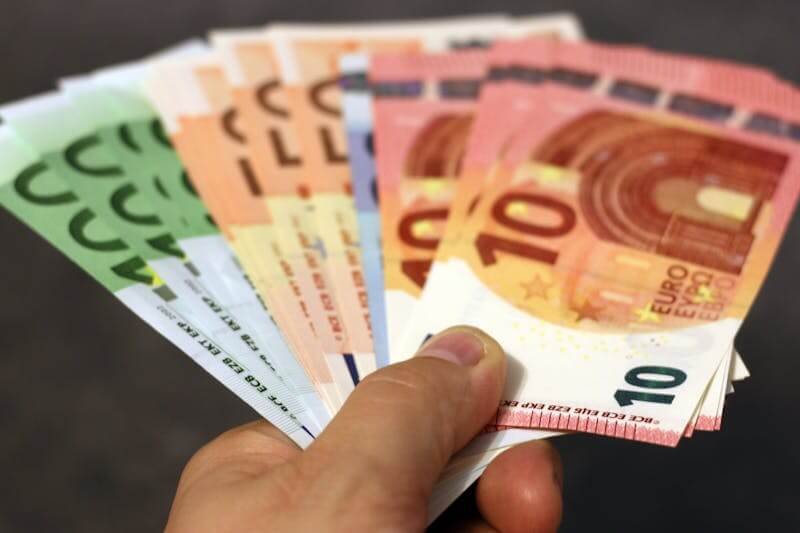 une main tient une liasse de billet pour illustrer la section payer en euros