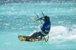 un homme tient d'une main un kite surf au cap vert, il maîtrise,