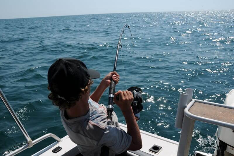 Un homme pêche sur un bateau au cap-Vert, et il a une touche d'un gros poisson.